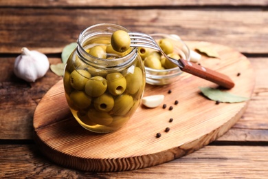 Photo of Glass jar of pickled olives on wooden table