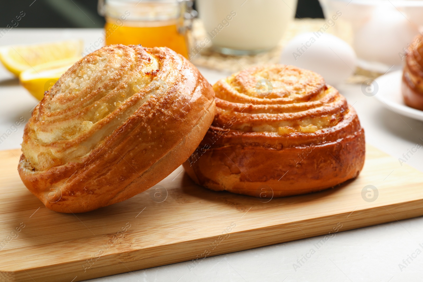 Photo of Wooden board with tasty buns on table, closeup. Fresh from oven