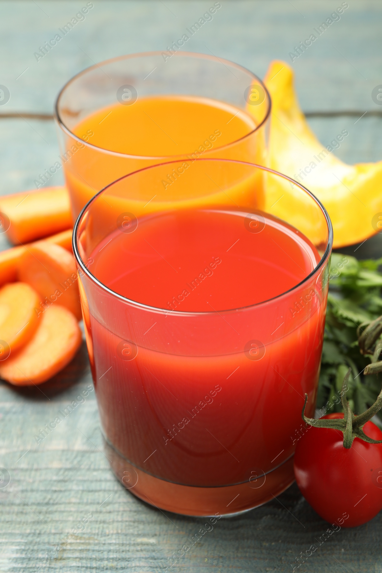 Photo of Delicious vegetable juices and fresh ingredients on blue wooden table, closeup