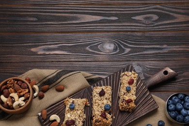 Tasty granola bars and ingredients on wooden table, flat lay. Space for text