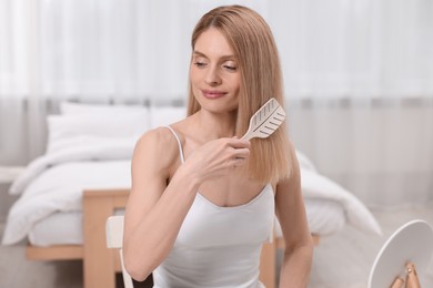 Photo of Beautiful woman brushing her hair in bedroom
