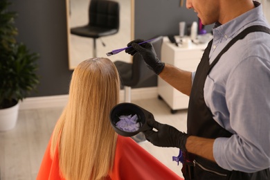 Photo of Professional hairdresser dying hair in beauty salon, closeup