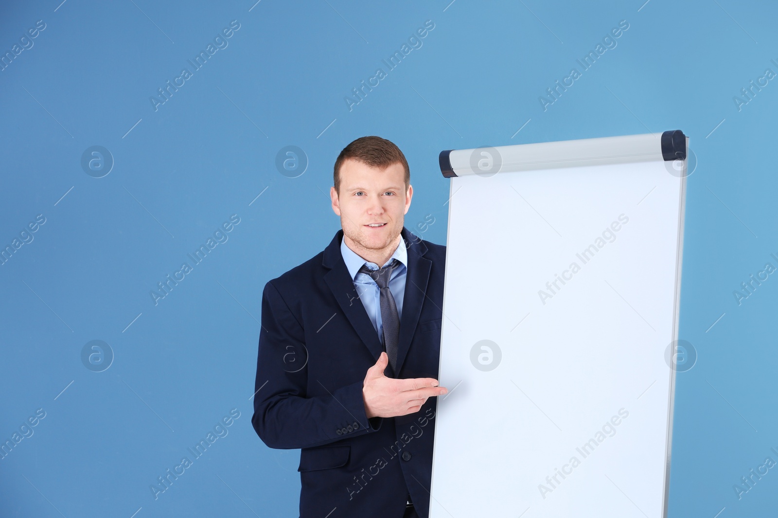 Photo of Business trainer giving presentation on flip chart board against color background