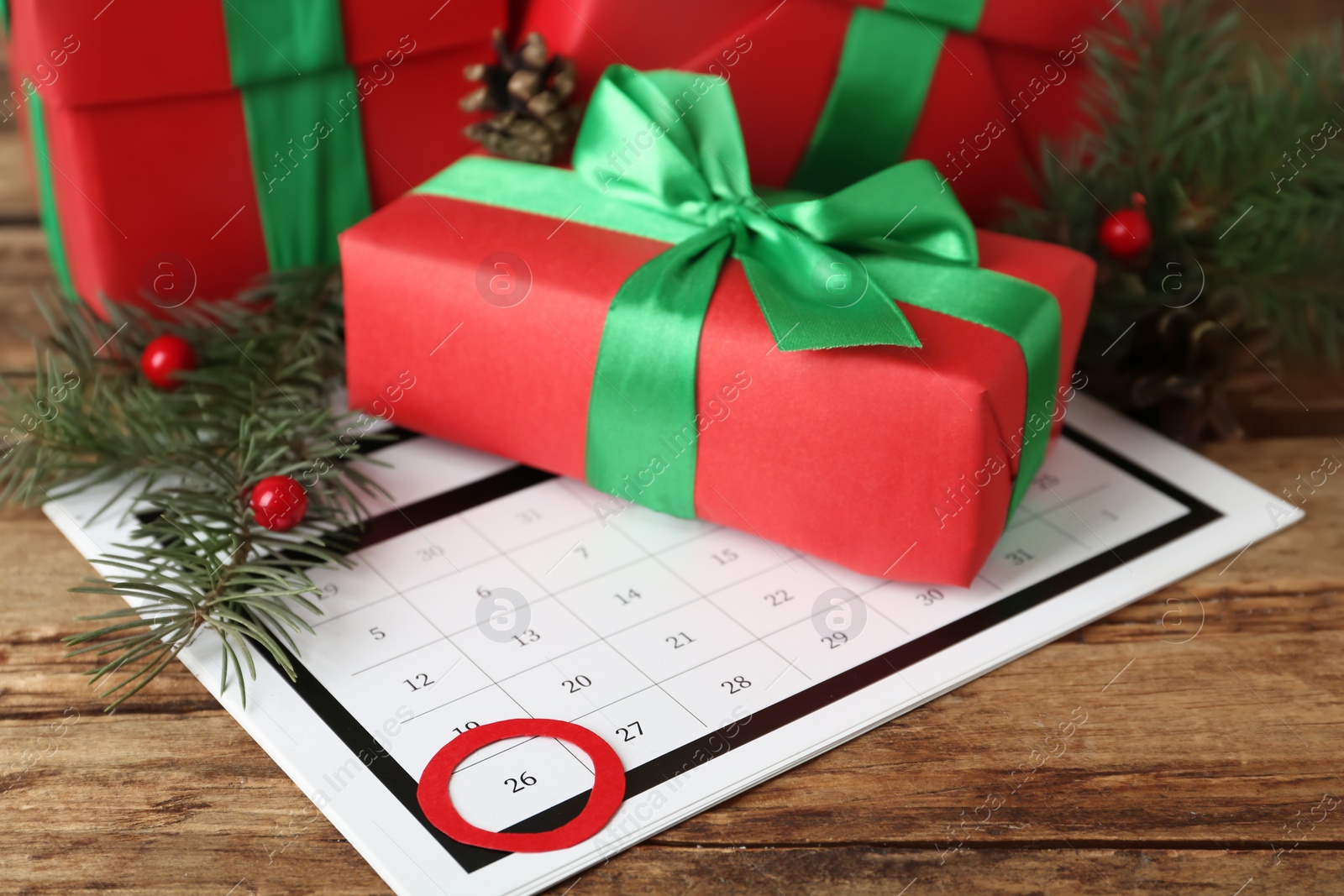 Photo of Calendar with marked Boxing Day date and gifts on wooden background, closeup