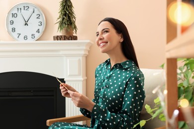 Happy woman holding Christmas greeting card in living room