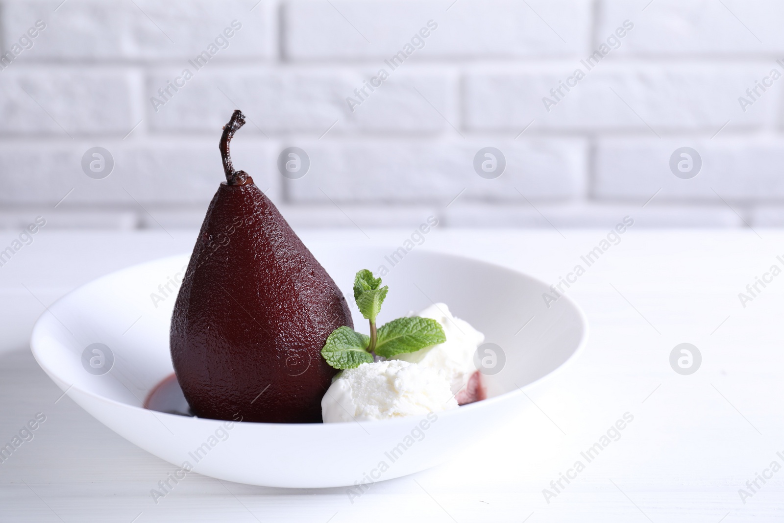 Photo of Tasty red wine poached pear with mint and Ice cream on white wooden table, closeup. Space for text