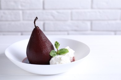 Tasty red wine poached pear with mint and Ice cream on white wooden table, closeup. Space for text