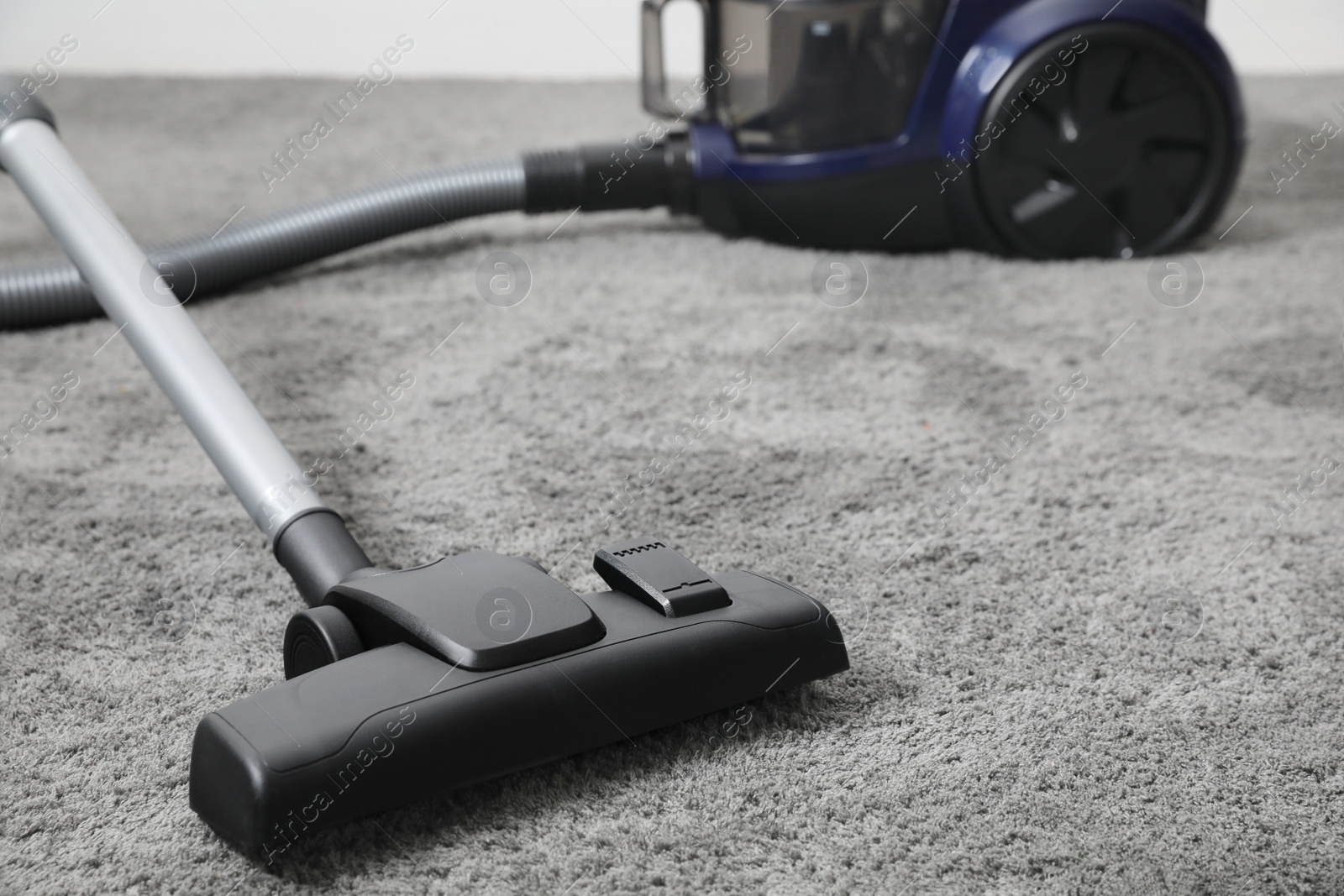 Photo of Modern vacuum cleaner on carpet indoors, closeup