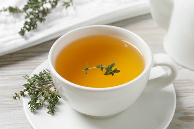 Photo of Aromatic herbal tea with thyme on white wooden table, closeup