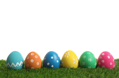 Photo of Colorful Easter eggs in green grass on white background