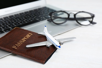 Composition with passport, laptop and toy plane on light background. Travel agency