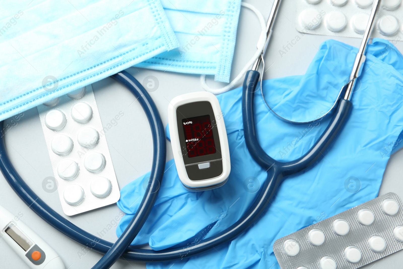 Photo of Flat lay composition with modern fingertip pulse oximeter and medical items on white background