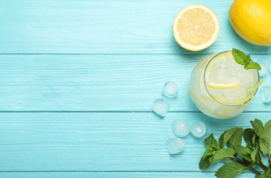 Flat lay composition of cocktail with vodka, ice and lemon on blue wooden table. Space for text