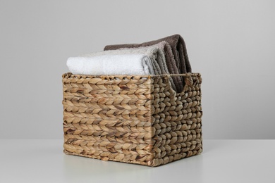 Photo of Wicker basket with clean soft towels on light background