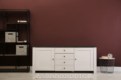 Photo of Modern room interior with chest of drawers near brown wall