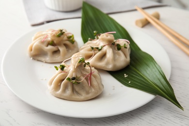 Photo of Plate with tasty baozi dumplings on white wooden table