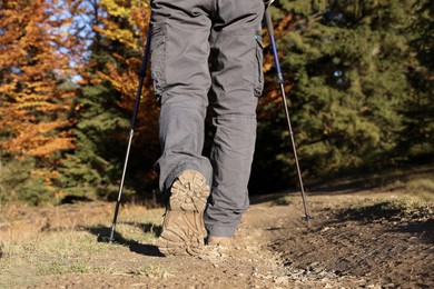 Photo of Hiker with trekking poles walking outdoors on sunny day, closeup