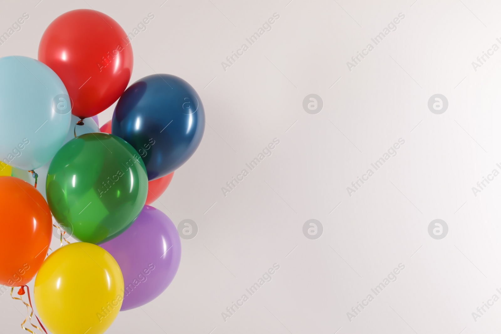 Photo of Bunch of bright balloons on light background, space for text. Celebration time