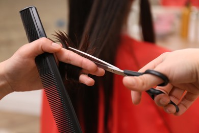 Photo of Stylist cutting hair of client in professional salon, closeup