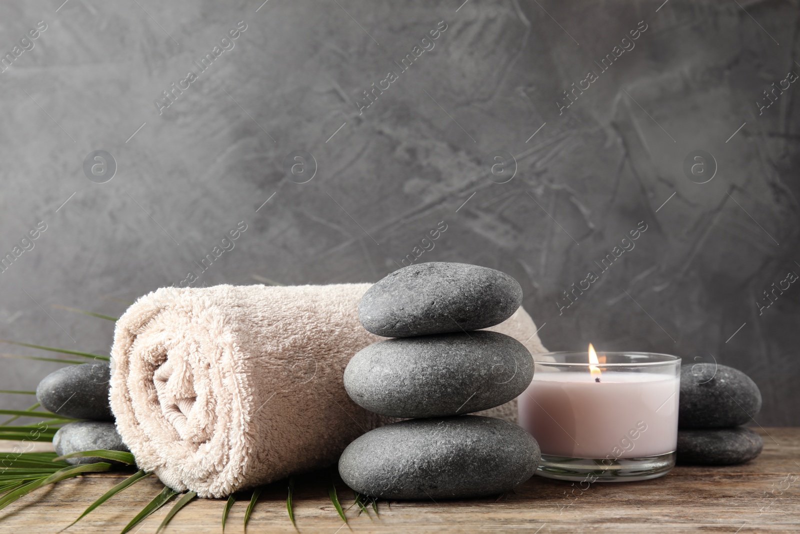 Photo of Composition with zen stones, towel and candle on table against grey background