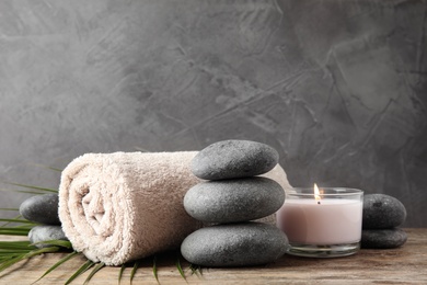 Composition with zen stones, towel and candle on table against grey background