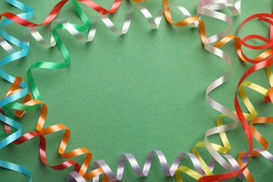 Photo of Frame of colorful serpentine streamers on green background, flat lay. Space for text