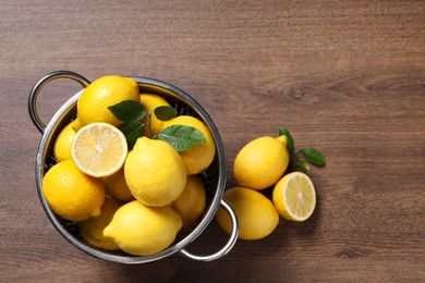 Photo of Fresh lemons and green leaves on wooden table, top view. Space for text