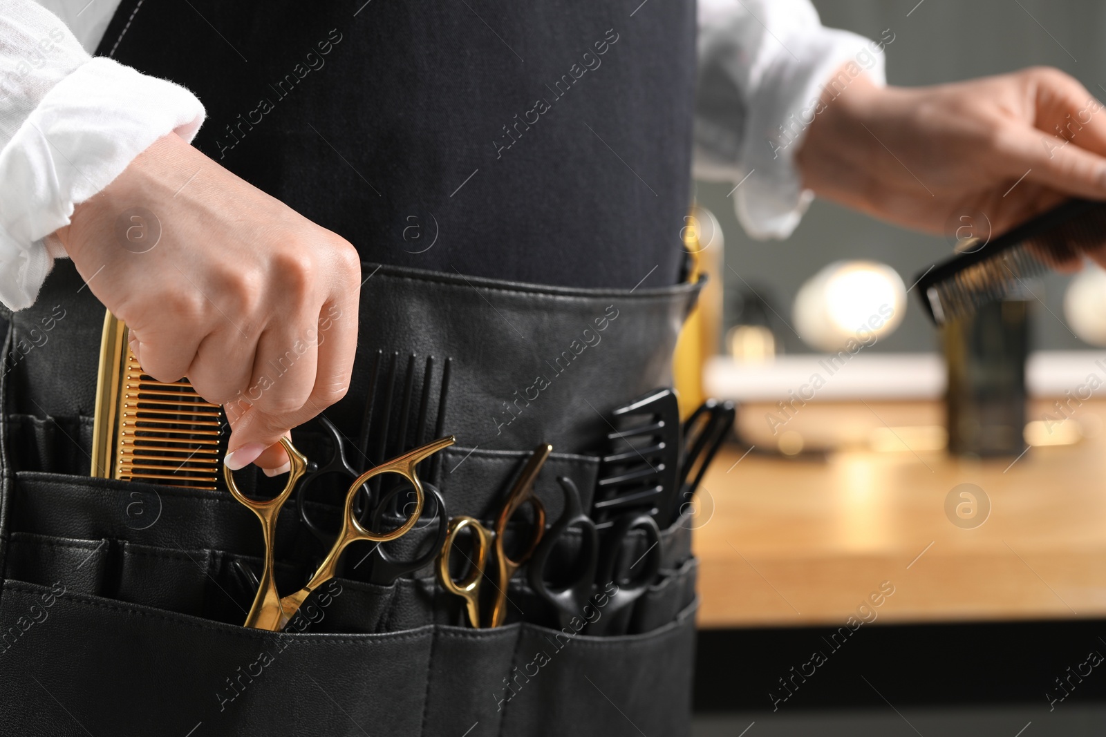 Photo of Hairstylist with professional tools in waist pouch in salon, closeup