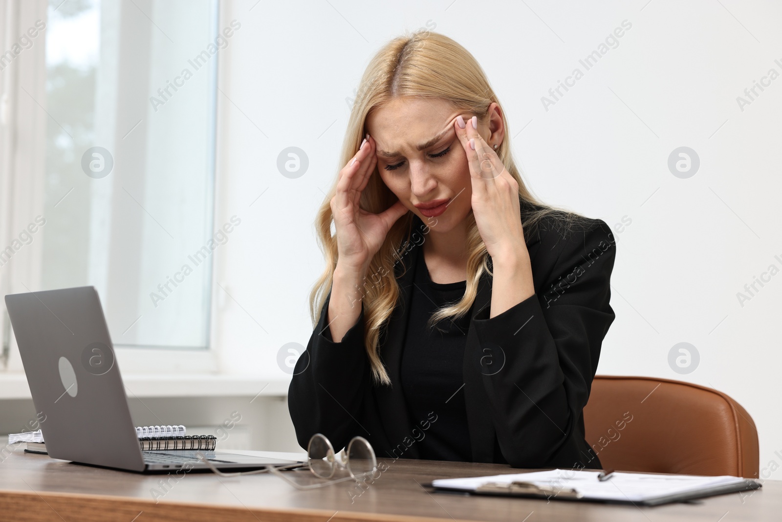 Photo of Overwhelmed woman at wooden table in office