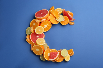 Letter C made with citrus fruits on blue background as vitamin representation, flat lay