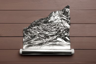 Photo of Roll of aluminum foil on wooden table, top view