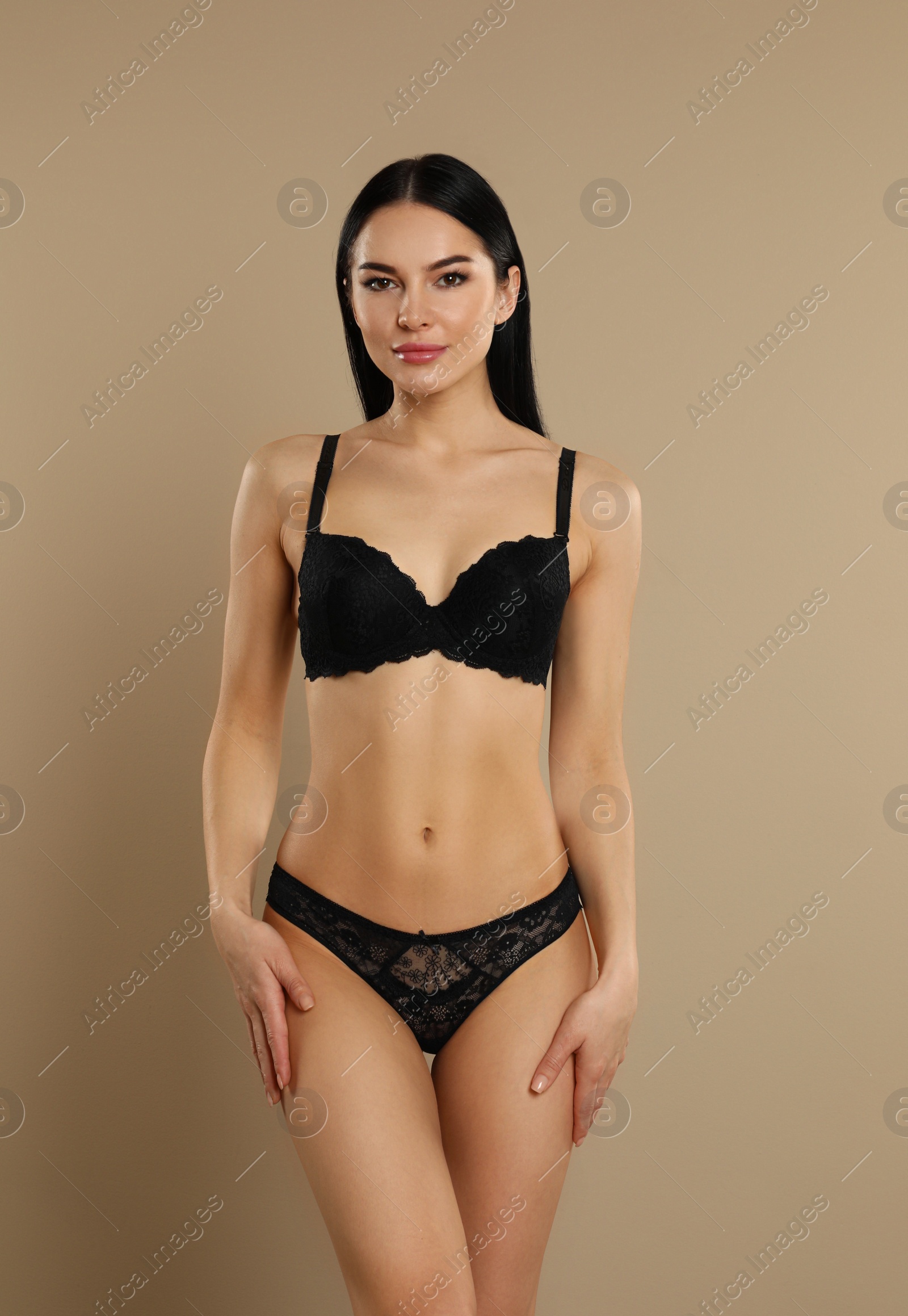 Photo of Beautiful young woman in black underwear on beige background