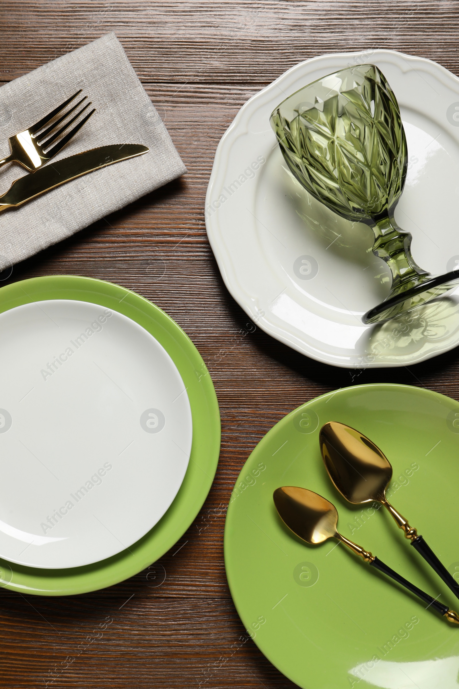 Photo of Beautiful ceramic plates, glass and cutlery on wooden table, flat lay