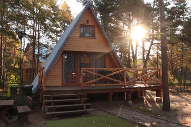 Picturesque view of modern wooden house with veranda near forest on sunny day