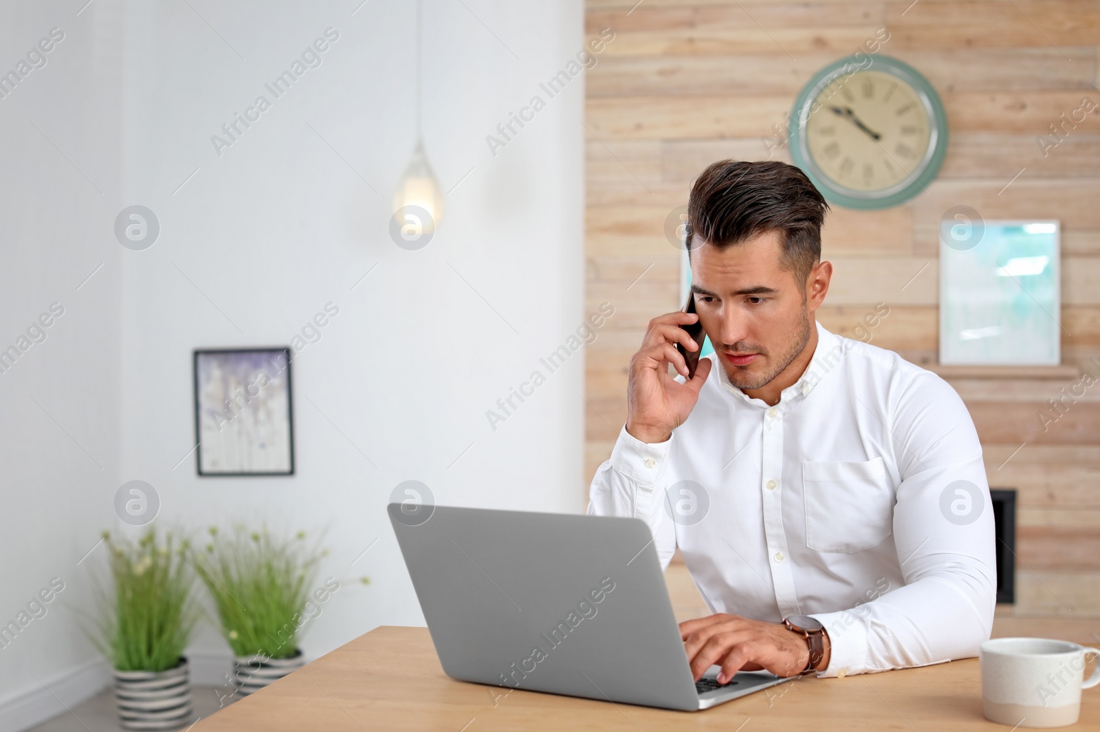 Photo of Handsome young man talking on phone in office