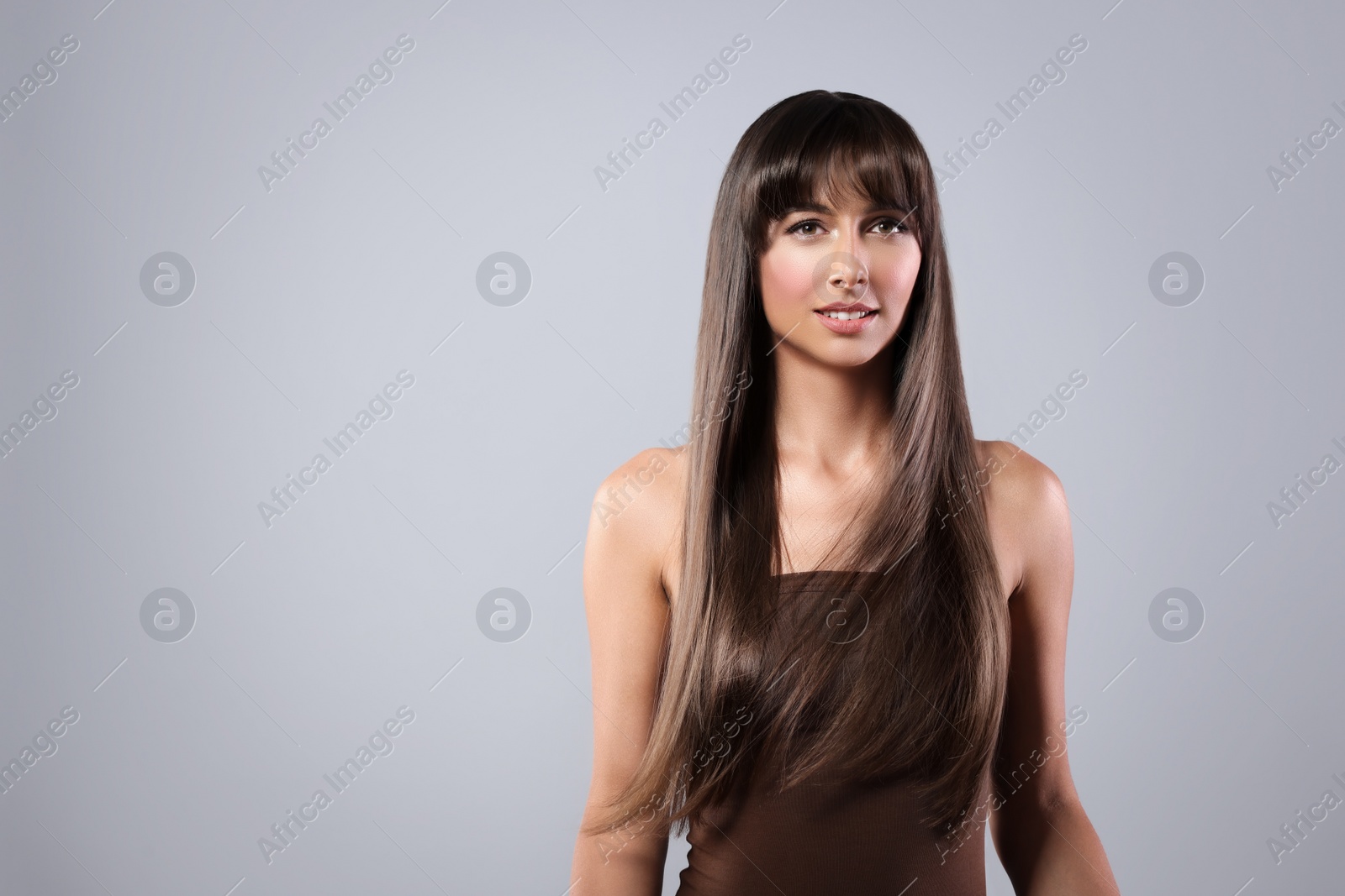 Image of Attractive woman with shiny straight hair on grey background, space for text. Professional hairstyling
