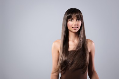Image of Attractive woman with shiny straight hair on grey background, space for text. Professional hairstyling