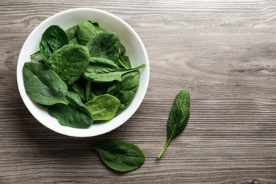 Photo of Fresh green healthy spinach leaves on wooden table, flat lay. Space for text