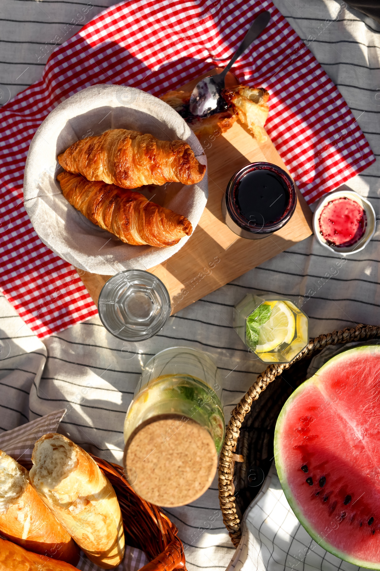 Photo of Delicious food and drink on striped blanket outdoors, flat lay. Picnic season