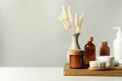 Photo of Different bath accessories and spikes on white table against grey background. Space for text