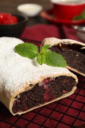 Delicious strudel with cherries and poppy seeds on table, closeup