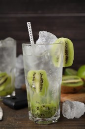 Glass of refreshing drink with kiwi on wooden table, closeup