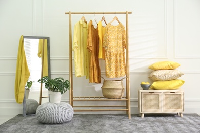 Photo of Stylish dressing room with clothes rack. Interior design in grey and yellow colors