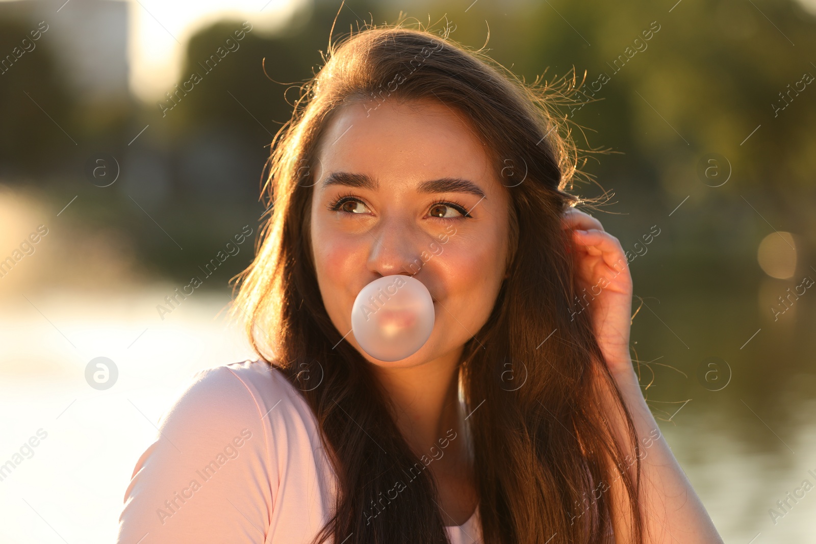 Photo of Beautiful young woman blowing bubble gum outdoors