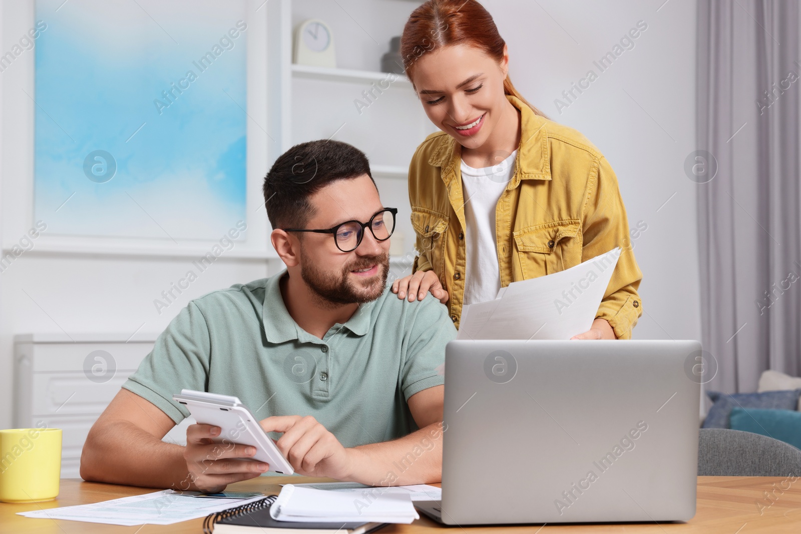 Photo of Couple calculating taxes for online payment at table in room