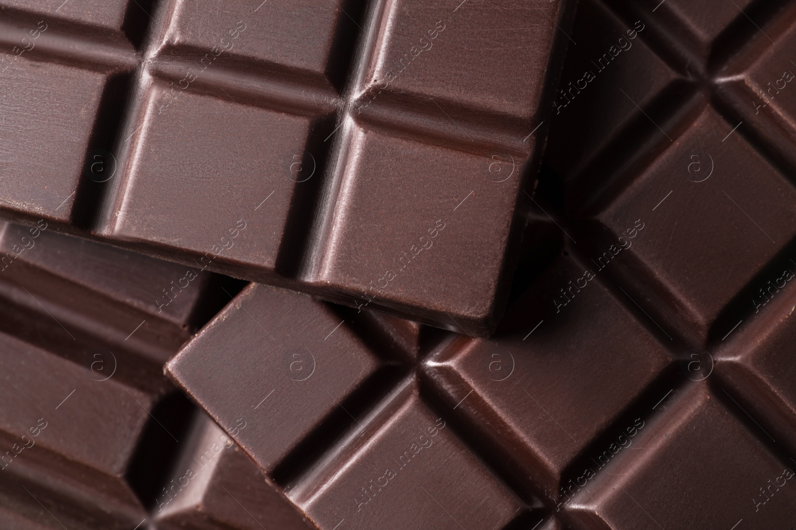 Photo of Many delicious dark chocolate bars as background, top view