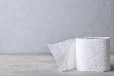 Photo of Roll of toilet paper on grey table. Space for text