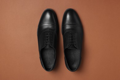 Photo of Pair of leather men shoes on brown background, top view