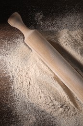 Pile of flour and rolling pin on wooden table, top view