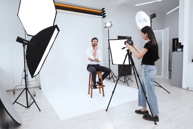 Photo of Professional photographer working with handsome model in modern photo studio